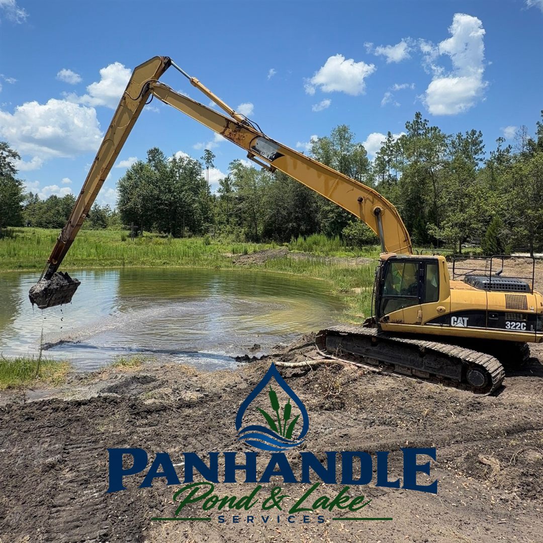 Long reach excavator dredging muck from a pond
